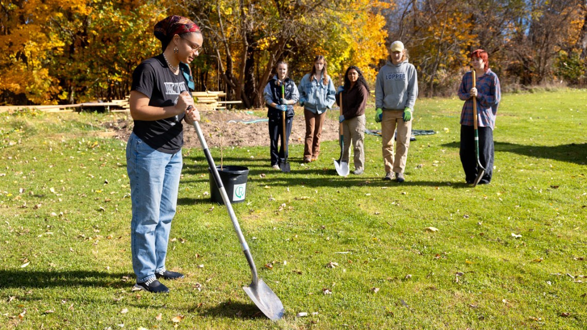 Gracekelly Fulton '24, co-lead of the Sustainable Landscapes team, prepares to plant a wild plum tree outside Onondaga Nation School.