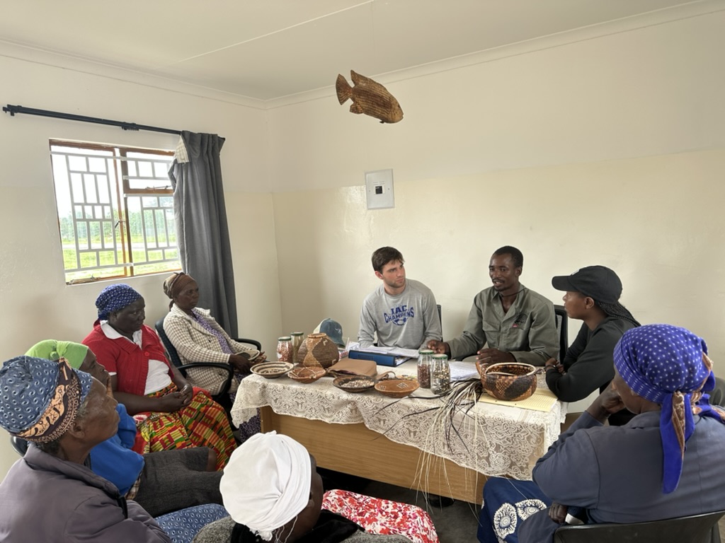 Logan Bonn ’25 (center, in gray shirt) and his research team conduct interviews with members of the basket-weaving cooperative in Samochima, Botswana. Provided.